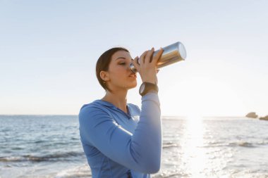 Kumsalda su içen kadın