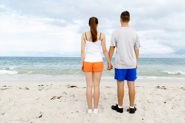 Jong koppel op zoek doordachte terwijl staande naast elkaar op het strand — Stockfoto