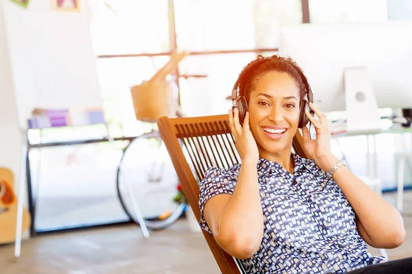 Portrait of smiling afro-american office worker sitting in offfice with headphones — Stock Photo, Image