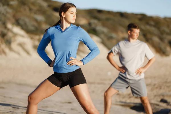 Jong (echt) paar op het strand training samen — Stockfoto