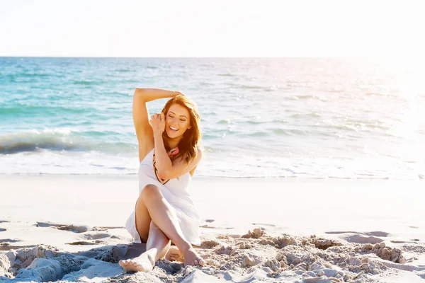 Mujer joven sentada en la playa — Foto de Stock