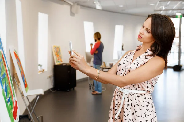 Mujer joven caucásica de pie en la galería de arte frente a las pinturas —  Fotos de Stock