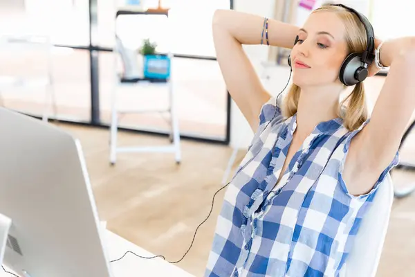 Kulaklıklar ile ofiste çalışan genç kadın