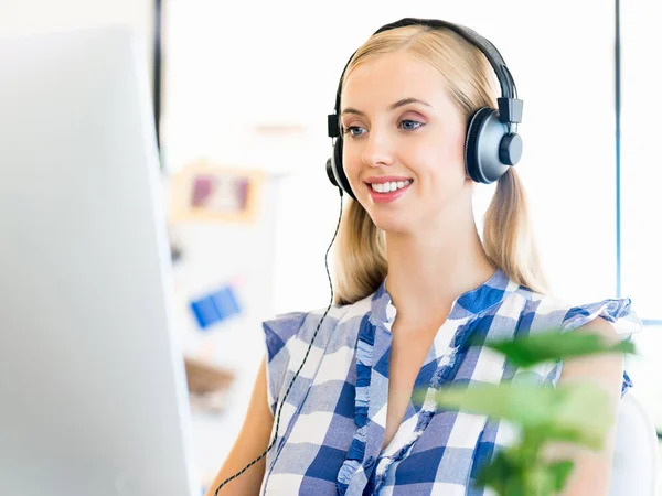Young woman working in office with headphones — Stock Photo, Image