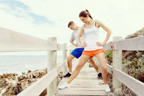 Běžci. Mladý pár cvičení a stertching na pláži — Stock fotografie