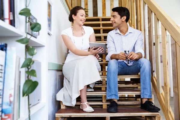 Portrait of two young people sitting at the stairs in office — Stock Photo, Image