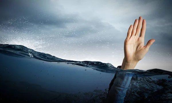 Hand of person drowning in water