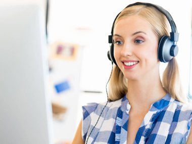 Kulaklıklar ile ofiste çalışan genç kadın