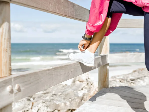 海辺で靴紐を結ぶ女性ランナー — ストック写真