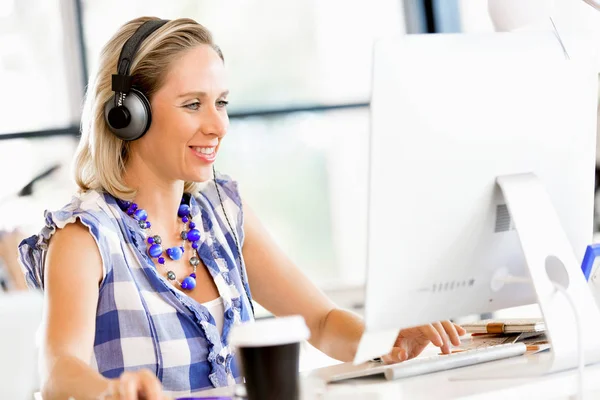 Jeune femme dans le bureau avec écouteurs — Photo