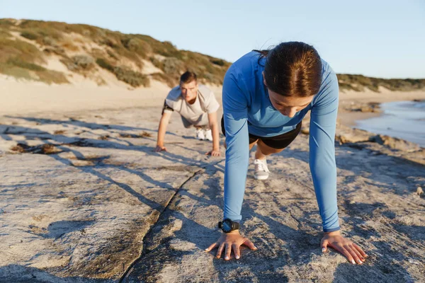 Mladý pár dělá push up na ocean beach — Stock fotografie