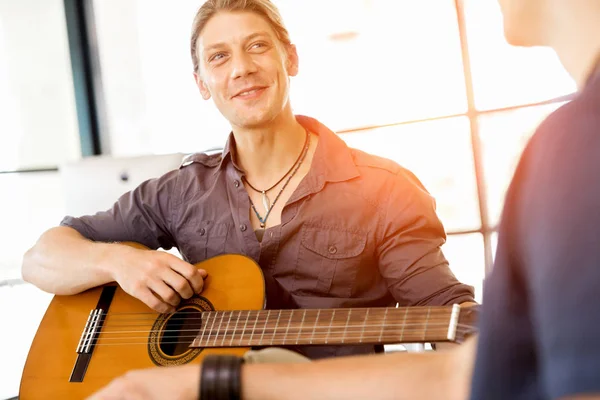 Mladý muž hraje na kytaru v úřadu — Stock fotografie