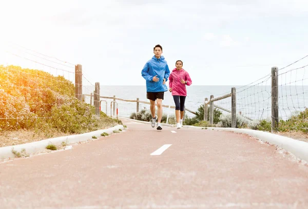 Pareja joven corriendo a lo largo de la orilla del mar — Foto de Stock