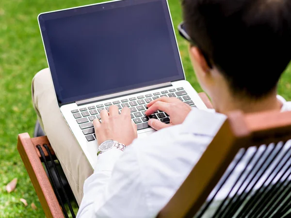 Młody biznesmen za pomocą laptopa siedząc na zewnątrz — Zdjęcie stockowe