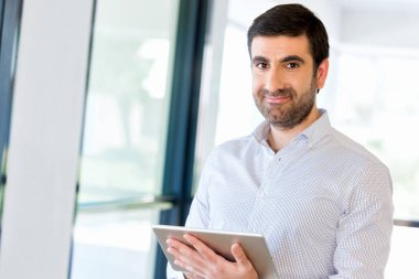 Genç yakışıklı işadamı onun touchpad ayakta kullanma office