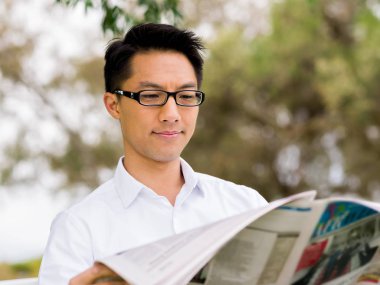 İş adamı parkta bir gazete okuyor