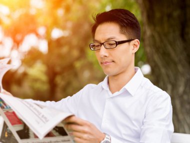 İş adamı parkta bir gazete okuyor