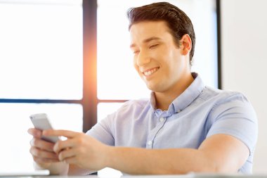 Kendine güvenen genç adam akıllı rahat kıyafet telefon tutarak