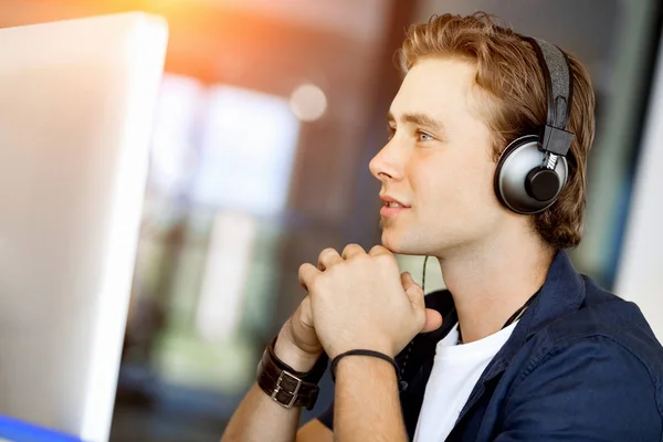 Mladý muž v kanceláři se sluchátky — Stock fotografie