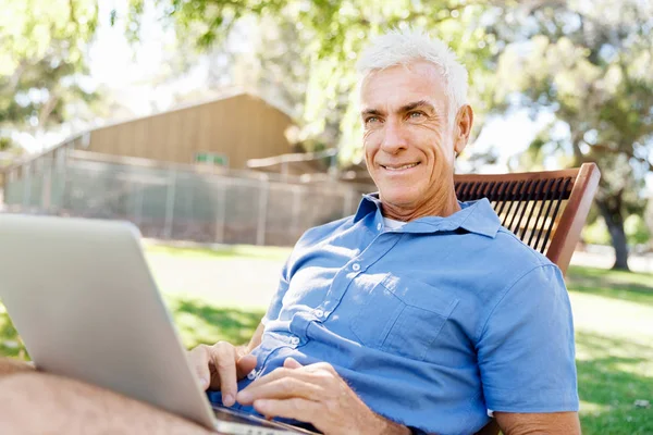 Senior férfi ül a parkban notebook — Stock Fotó