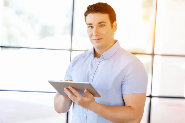 Giovane bell'uomo d'affari che usa il suo touchpad in piedi in ufficio — Foto Stock