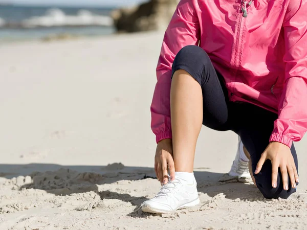 해변에서 신발끈을 매는 여성 러너 — 스톡 사진