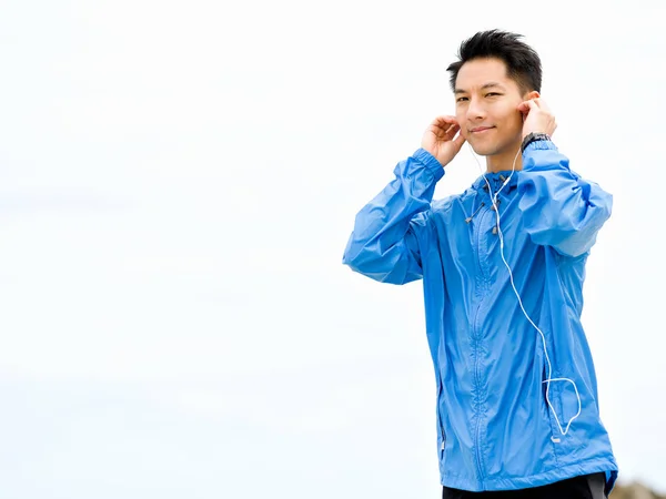 Sportieve man met koptelefoon aan de kust van de zee — Stockfoto