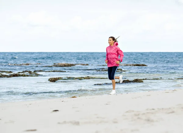 Mladá žena jogging na pláži — Stock fotografie
