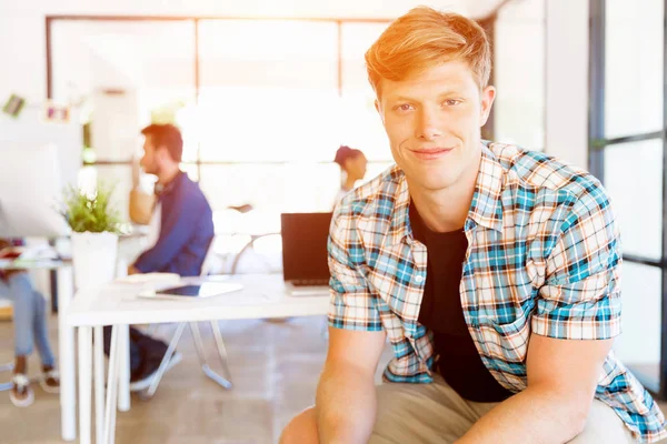 Young man sitting and looking at camera in office — Stock Photo, Image