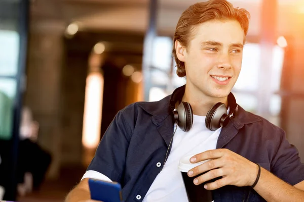 Självsäker ung man i smart fritidskläder som håller telefonen — Stockfoto