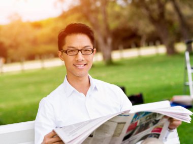 İş adamı parkta bir gazete okuyor