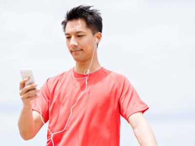 Deniz kıyısında kulaklık sportif adamla