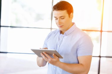 Genç yakışıklı işadamı onun touchpad ayakta kullanma office