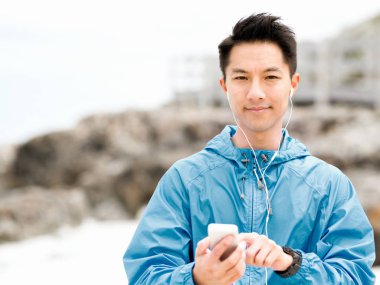 Deniz kıyısında kulaklık sportif adamla