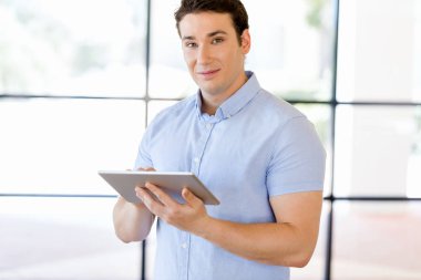 Genç yakışıklı işadamı onun touchpad ayakta kullanma office