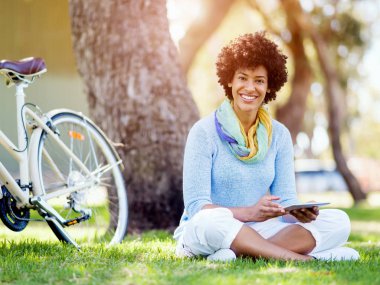 Parkta tablet kullanan genç bir kadın..