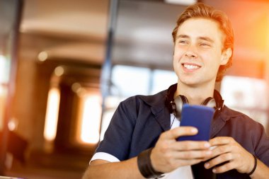 Kendine güvenen genç adam akıllı rahat kıyafet telefon tutarak