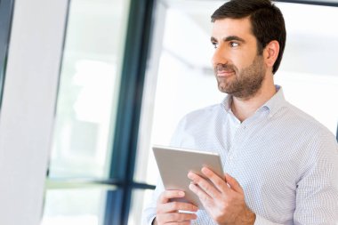 Genç yakışıklı işadamı onun touchpad ayakta kullanma office