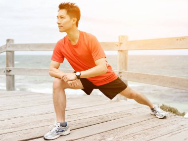 Genç adam sahilde egzersiz yaparak