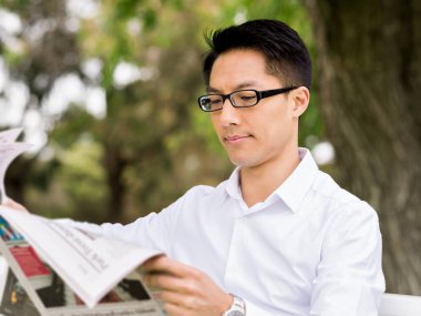 İş adamı parkta bir gazete okuyor