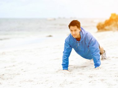 Genç adam sahilde egzersiz yaparak