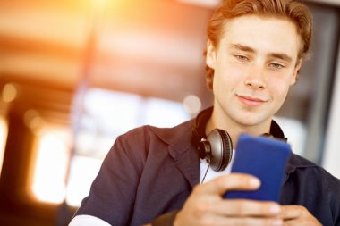 Kendine güvenen genç adam akıllı rahat kıyafet telefon tutarak