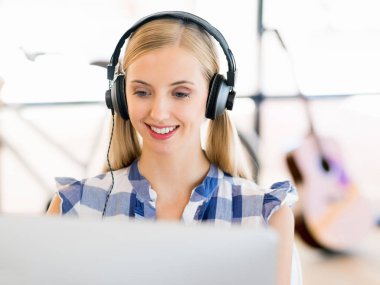 Kulaklıklar ile ofiste çalışan genç kadın