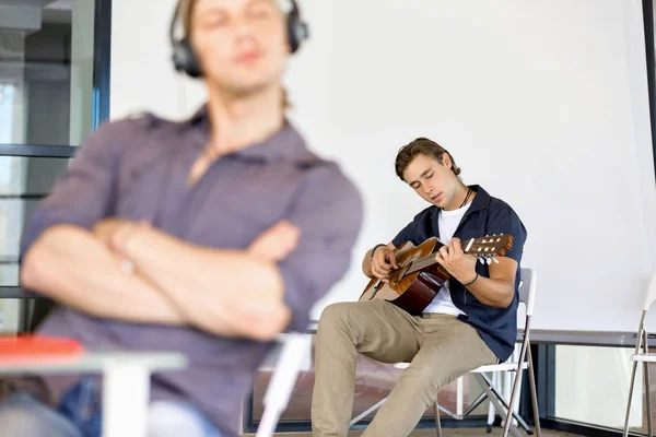 Jeune homme jouant de la guitare au bureau — Photo