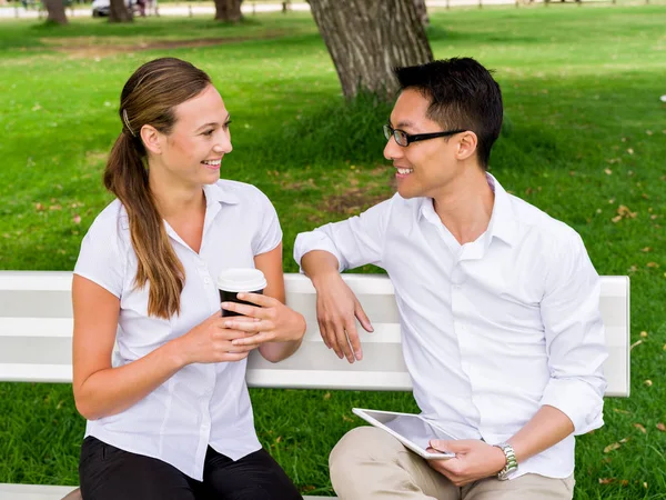 Портрет улыбающейся пары, сидящей в парке и разговаривающей — стоковое фото