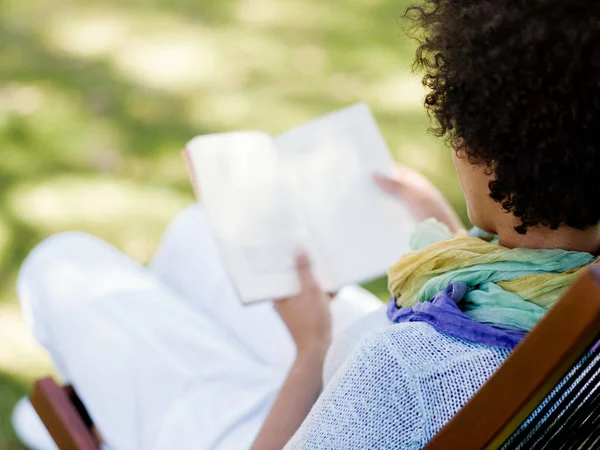 Jonge vrouw lezen van een boek in park — Stockfoto