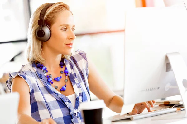 Ung kvinna i kontoret med hörlurar — Stockfoto