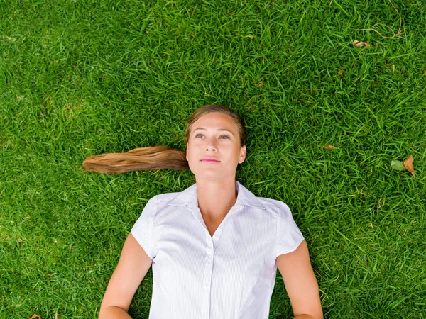 Mujer joven y bonita relajándose en una hierba — Foto de Stock