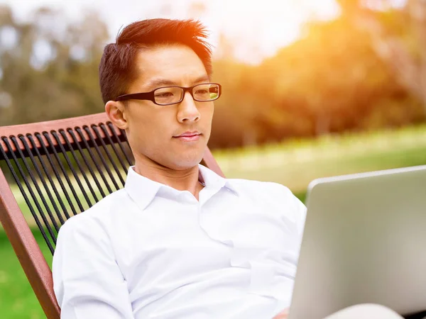 Fiatal üzletember használ laptop ülve a szabadban — Stock Fotó