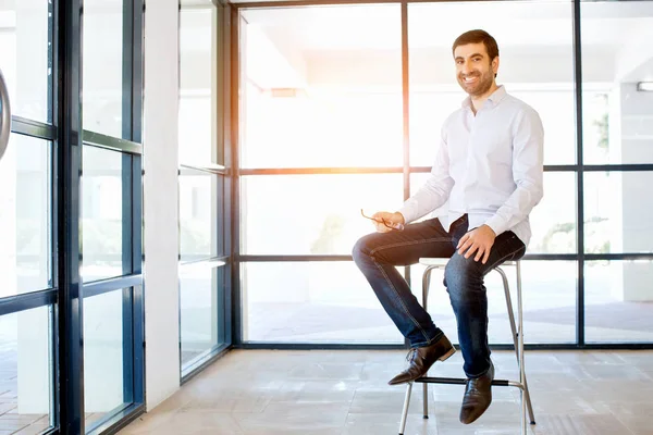 Jeune homme d'affaires assis sur un tabouret au bureau — Photo